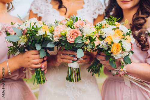 Bride with beautiful bridesmaids in lilac color dresses holding bouquets. Autumn in the Park. Sunny day. Close up. Copy space. 