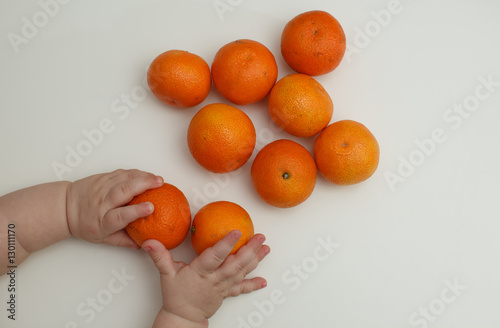 Children's hands and tangerine on a white background.