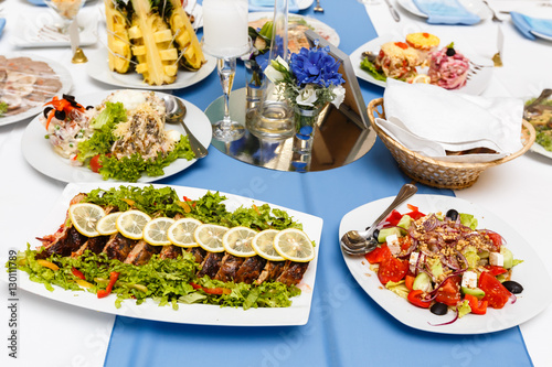 Fried fish and salads on a banquet table in restaurant