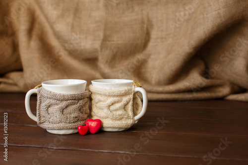 Cups of coffee with knitted cup holder near heart for valentine's day. Love coffee