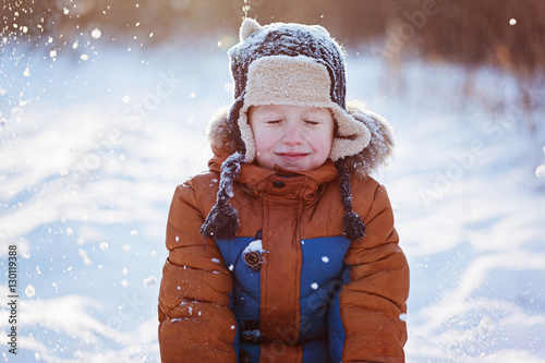 Happy child boy playing on a winter walk in nature during snowfall photo