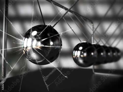 Newton's cradle with broken glass, silver cradle on dark surface
