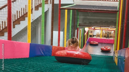 the little girl on the tubing rolls with slides in the play area