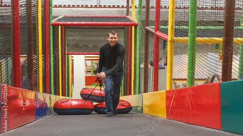 man picks up the hill three sleds in the play area. he smiles.