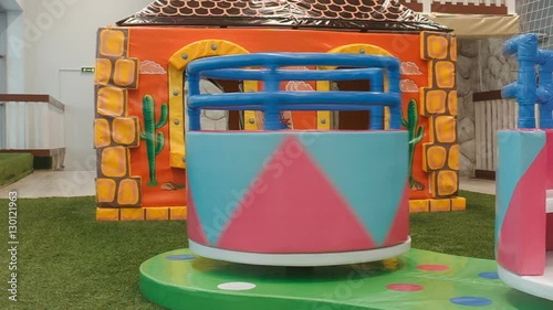 children round the carousel turns in the play area. Little girl climbs on it