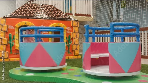 children round the carousel turns in the play area. Little girl climbs on it