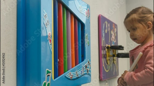 little girl learning to play the xylophone. Dad helps her.