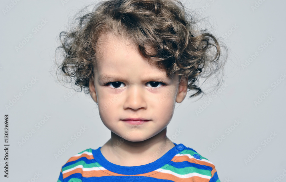 Beautiful curly toddler looking angry, sad boy being naughty Beautiful curly toddler looking angry, sad boy being naughty