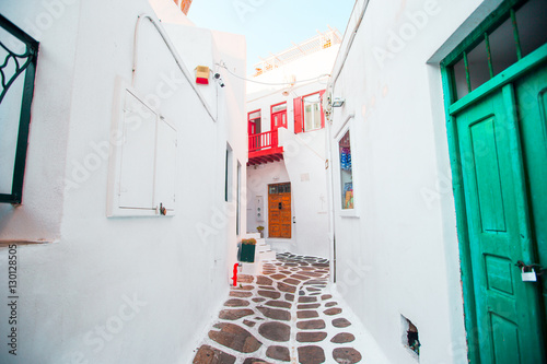 The narrow streets of greek island with white balconies, stairs and colorful doors. Beautiful architecture building exterior with cycladic style.