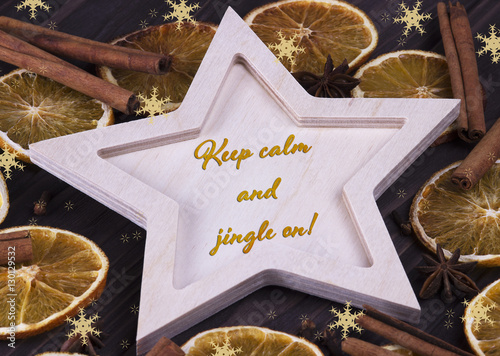 Christmas Xmas New Year Holiday greeting card with wooden star cinnamone star anice dried oranges snowflakes and text Keep calm and jingle on photo