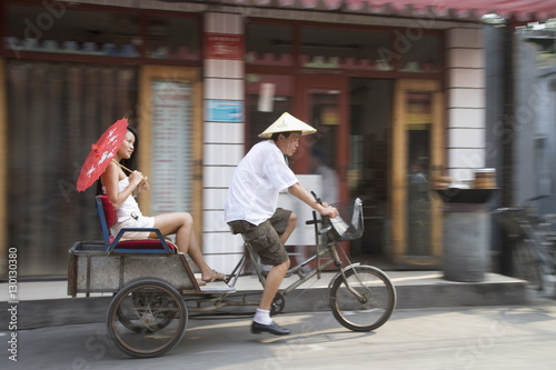Asian woman (Chinese-Thai) riding in cycle rickshaw, Hutong District, Beijing, China photo