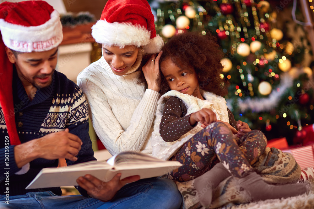 Afro American family look at book for Christmas Afro American family look at book for Christmas