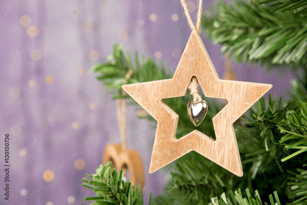 Christmas decoration with wooden star with heart on christmas tree and bokeh light background. Winter, Christmas, New Year decoration – star prepared from natural, solid wood.. Copy space. Closeup.