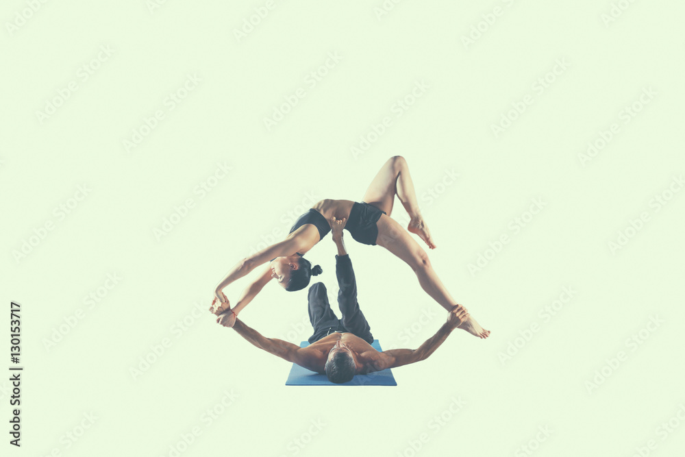 Young couple practicing acro yoga on mat in studio together Young couple practicing acro yoga on mat in studio together