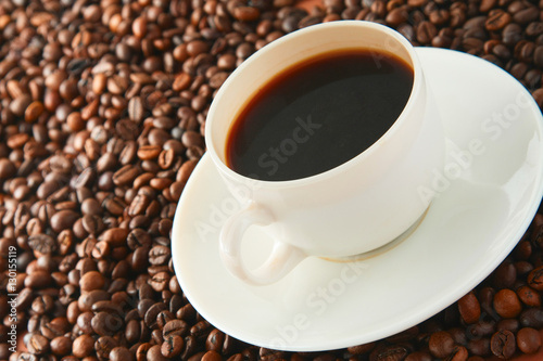 Cup of coffee on beans as background