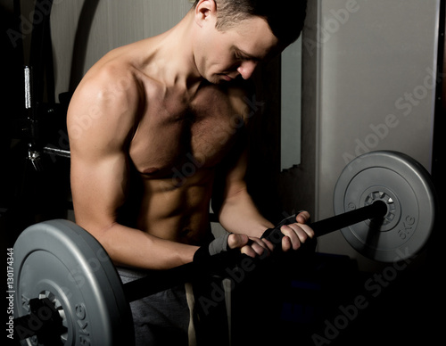 Handsome athletic man with dumbbell on a darck background