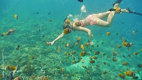 Underwater footage of a girl snorkeling with a group of colorful fish on the coral reef in Nusa Penida, Bali, Indonesia. photo