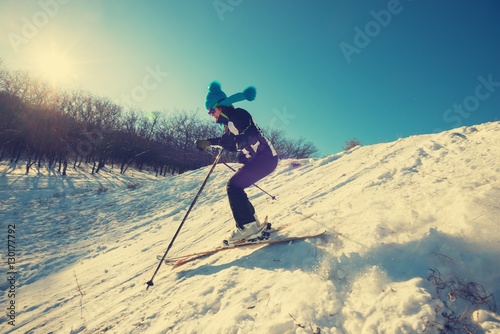 Woman in funny cap skiing downhill in winter forest