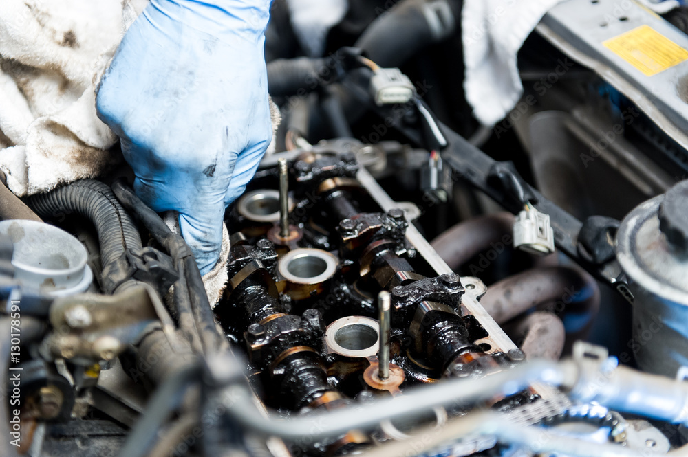 Mechanic cleaning a car's engine with a rag Mechanic cleaning a car's engine with a rag