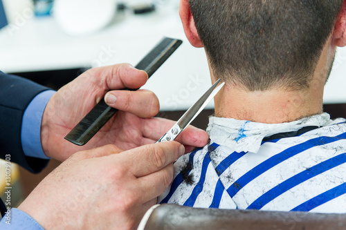 Barber cutting customer's hair with a pair of scissors