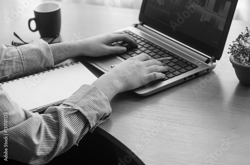 Young woman's hands working at a laptop, black and white image