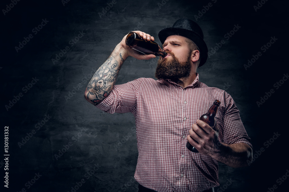 Bearded male in a cylinder hat, drinking beer from a bottle. Bearded male in a cylinder hat, drinking beer from a bottle.