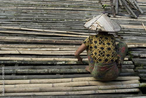Iban tribeswoman mending bamboo longhouse verandah floor, Lemanak River, Sarawak, Malaysian Borneo, Malaysia photo