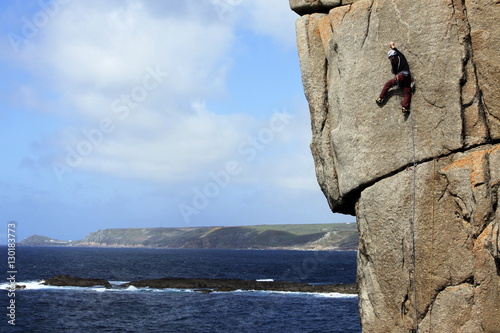 A climber scales cliffs at Sennen Cove, Cornwall photo