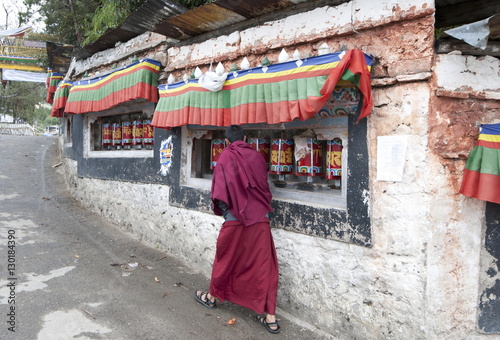 Buddhist monk turning prayer wheels outside Tawang Buddhist monastery, Arunachal Pradesh photo