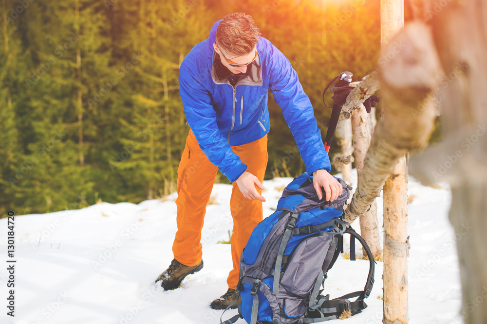The climber pulls things out of the backpack. The climber pulls things out of the backpack.