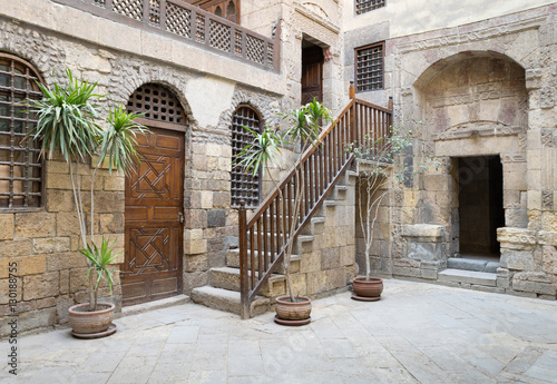Courtyard of Beit El Set Waseela (Waseela Hanem House), with wooden closed door and two windows with interleaved wooden grid and stair with wooden handrail, Medieval Cairo, Egypt photo