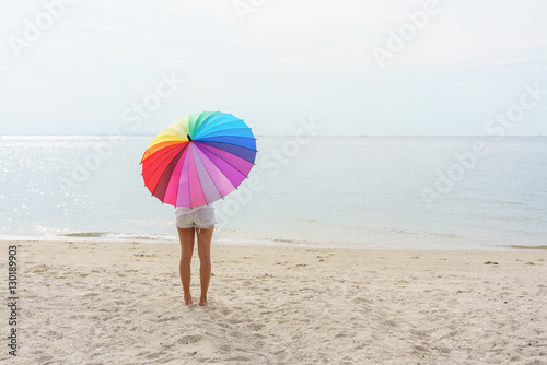 Asian young woman holding rainbow umbrella on the beach © PK4289