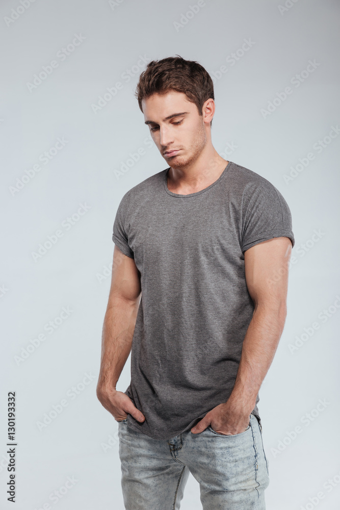 Sad upset young man in hat standing and looking down