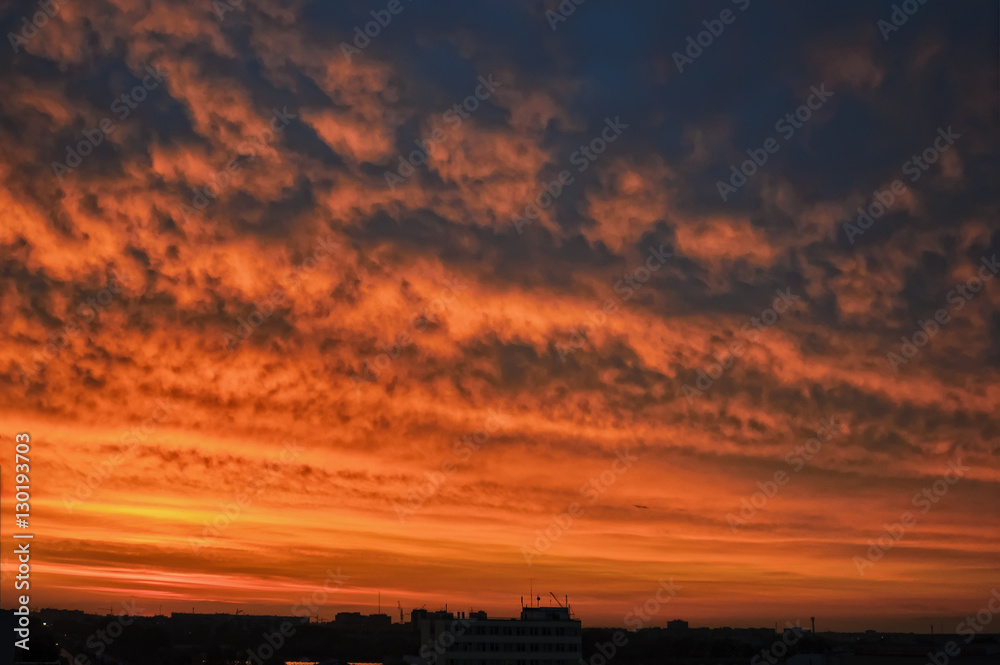 Dramatic sunset and sunrise sky over residential building roofs