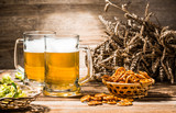 Two mugs of foam beer with pretzels, wheat and hops