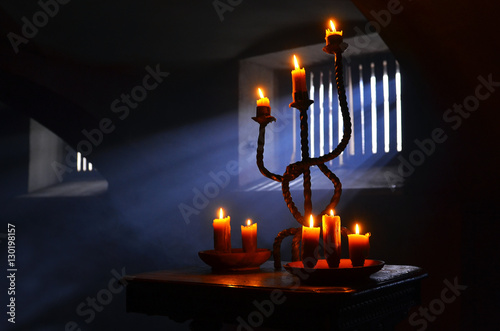 Antique candle burning in a dark room. Christmas Eve, divination, yuletide. Christmas backgrounds. holiday rituals, religion, spirituality, zen. space for text, close-up, copy space.