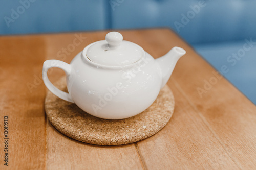 White beautiful teapot on a stand on a table in a cafe