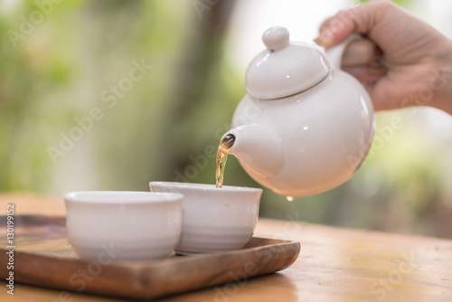 Teapot pouring tea in cup
