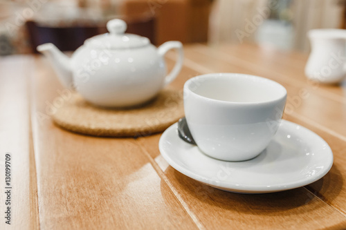 Empty tea mug on cafe table with teapot