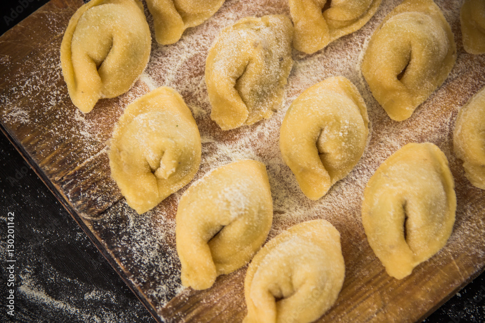 Freshly prepared Italian tortellini on wooden board  top view