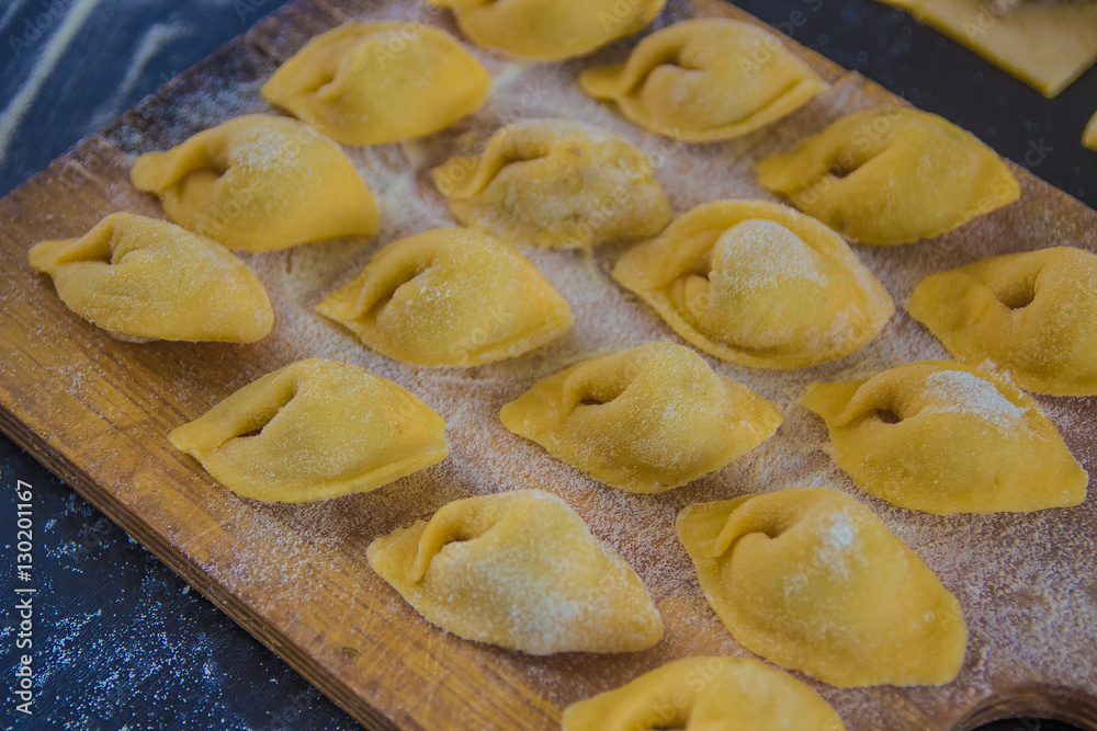 Homemade tortellini with mushrooms on black background close up