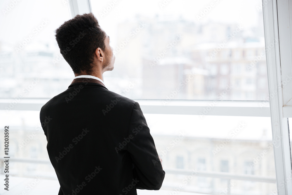 Back view of African business man looking at window Back view of African business man looking at window