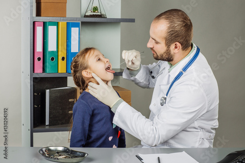 man doctor examining child mouth in clinic