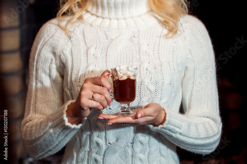 Hot chocolate or cocoa with marshmallows, Cup against a white sweater. Woman enjoying drink