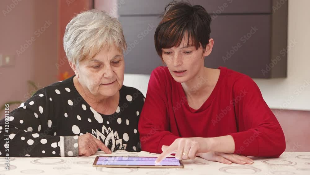 generations compared: young woman explains to her grandmother tablet technology generations compared: young woman explains to her grandmother tablet technology