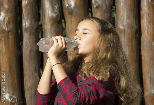 Girl drinks water from a plastic bottle