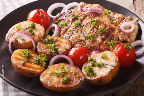 Chicken meat grilled with new potatoes and tomatoes close-up. horizontal