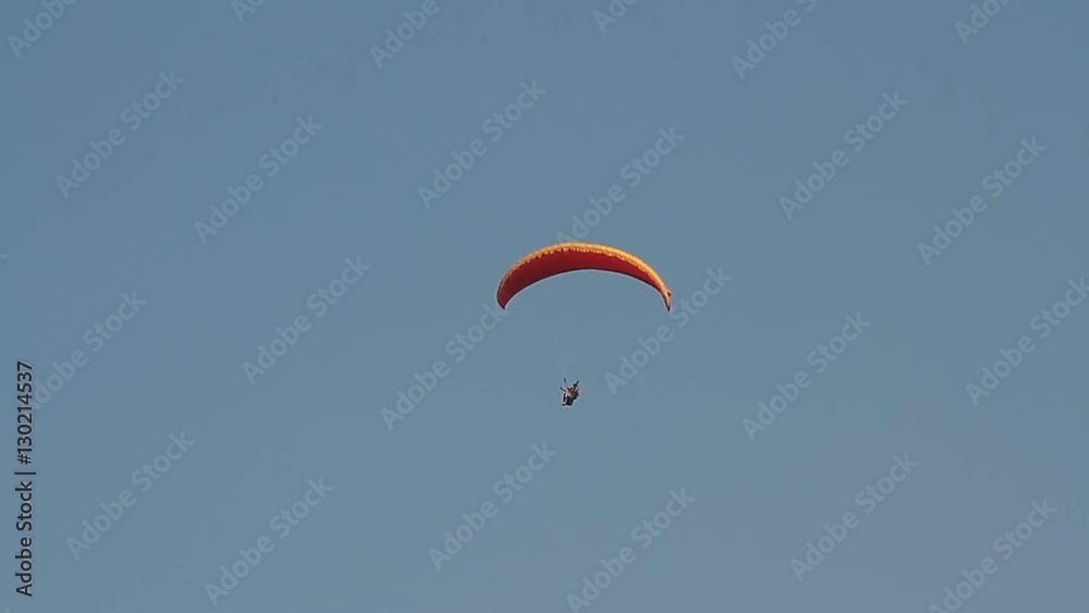 Paragliding over the mountains against clear blue sky Paragliding over the mountains against clear blue sky
