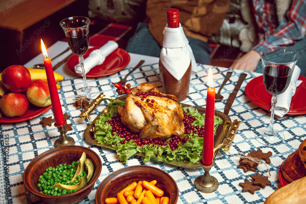 Roasted chicken, table setting. Thanksgiving table served with baked turkey, decorated with lettuce and pomegranate seeds. Christmas dinner by candlelight