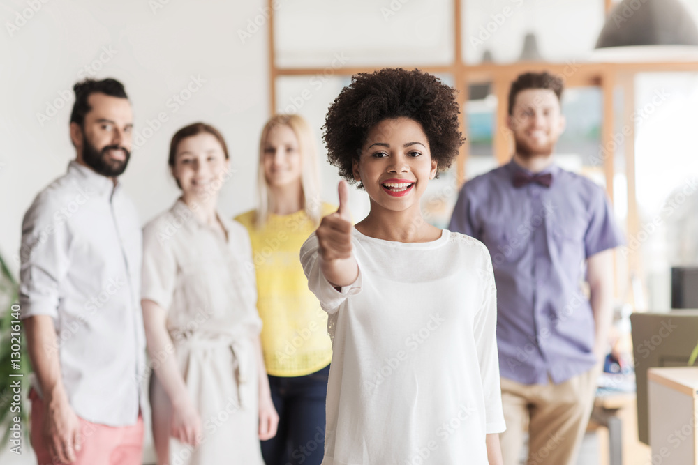 Obraz premium woman showing thumbs up over creative office team